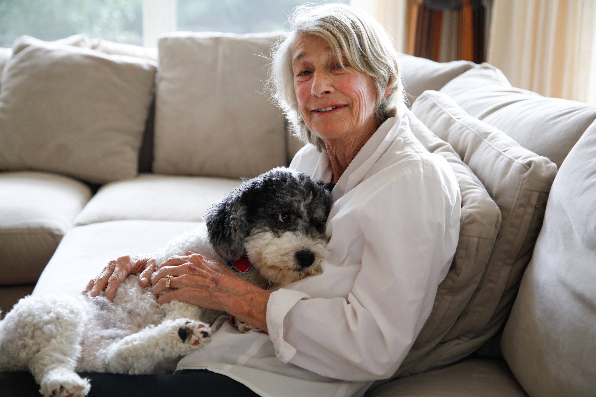 hình ảnh nữ thi sĩ Mary Oliver ngồi trên ghế sofa ôm chú chó của mình